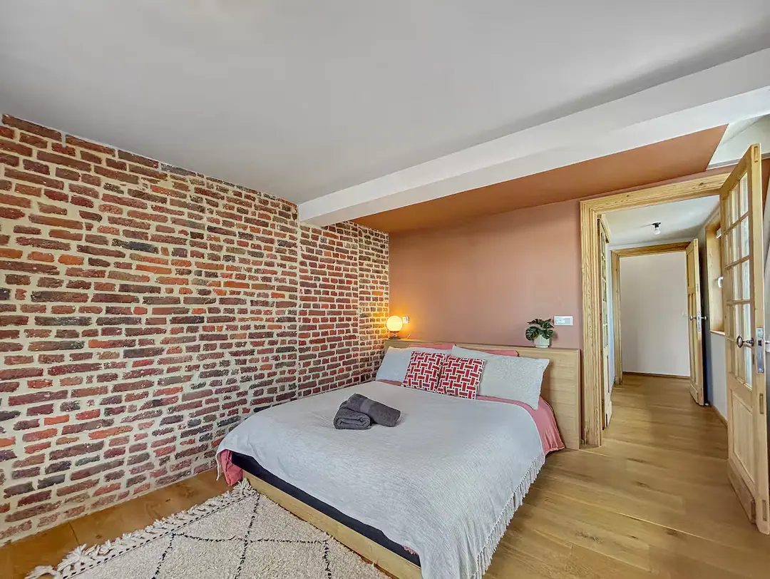 Chambre sous un mur de briques apparentes.